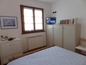 ein Schlafzimmer mit weißen Schränken, einem Fenster und einem Bett in der Unterkunft Baita de Eliseo B&B in Valdisotto