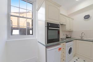 een keuken met witte kasten en een raam bij Exclusive Mayfair Apartment Suite in Londen