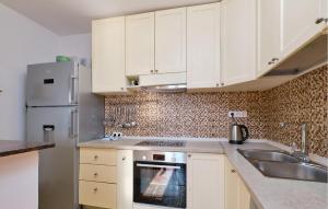 a kitchen with white cabinets and a sink and a refrigerator at 3 Bedroom Nice Apartment In Mali Losinj in Mali Lošinj +21 photos