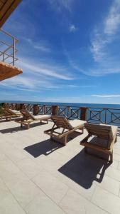 a row of wooden benches sitting on a patio overlooking the ocean at Hermosa Siute frente al mar en Tolu-Sucre in San Silvestre