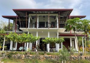 una grande casa bianca con balcone e alberi di Ayurveda Suwetha Villa a Bentota