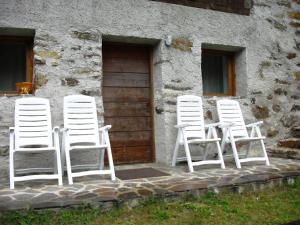 4 sillas blancas sentadas fuera de un edificio en Baita Misseroni Quadrilocale, en Rabbi