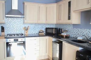 a kitchen with white cabinets and a stove top oven at Pass the Keys 2 bed town centre flat Llanelli · Modern and bright town centre flat in Llanelli in Llanelli