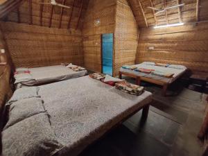 a room with three beds in a wooden room at Hill Stone View Hampi in Hampi