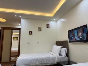 a room with two beds and a flat screen tv at Pyramids Gardens Hotel - فندق حدائق الاهرام in Cairo