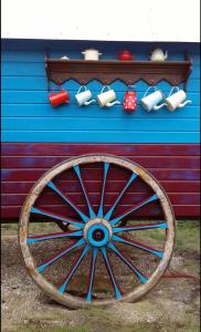 ein vor einem Gebäude sitzendes Wagenrad aus Holz in der Unterkunft Roulotte "Grain de Folie" in Waben