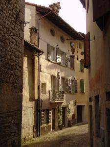 um beco com um edifício antigo com uma varanda em Residenza Dei Tolomei Polcenigo em Polcenigo