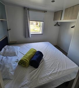 una camera con un letto con due cuscini sopra di Mobil Home (Clim, TV)- Camping Falaise Narbonne-Plage 4* - 003 a Narbonne-Plage