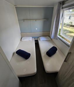 two beds in a small room with a window at Mobil Home (Clim, TV)- Camping Falaise Narbonne-Plage 4* - 003 in Narbonne-Plage