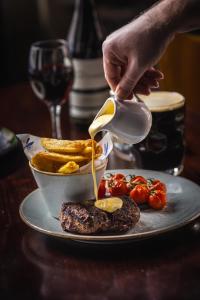 a person pouring sauce onto a steak and french fries at The Pied Bull in Chester