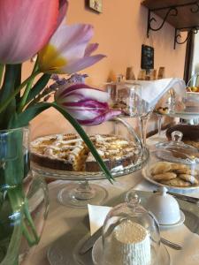 una mesa con pasteles y una flor en un jarrón en B&B La Casa della Nonna - L'Antico Fienile en San Martino al Cimino
