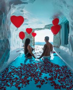 una pareja de pie en el agua con corazones en el suelo en Cavo Tagoo Mykonos, en Mykonos ciudad