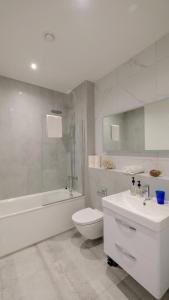a bathroom with a toilet and a tub and a sink at Stunning Acton Apartment With Patio in London