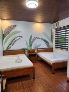 two beds in a room with a mural on the wall at BALAI MALINAWON - Balai 1 in General Luna