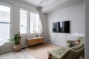 uma sala de estar com uma televisão, um sofá e uma cadeira em Kaunis ja toimiva uusi yksiö em Kuopio