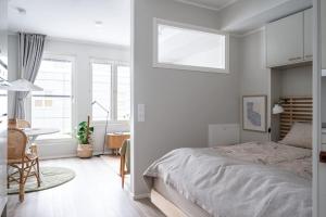 een witte slaapkamer met een bed, een tafel en een raam bij Kaunis ja toimiva uusi yksiö in Kuopio