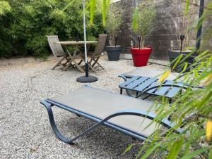 two picnic tables and an umbrella in a garden at Escapade Coquine in Ploërmel