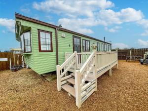 a green tiny house with a wooden porch at 6 Berth Dog Friendly Caravan In Hunstanton, Minutes From The Beach Ref 13013l in Hunstanton