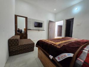 1 dormitorio con cama, silla y espejo en Corridor inn, en Derā Nānak