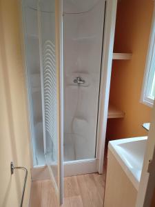 uma cabina de duche em vidro numa casa de banho ao lado de um lavatório em Camping la Vallée em Tour-d'Auvergne