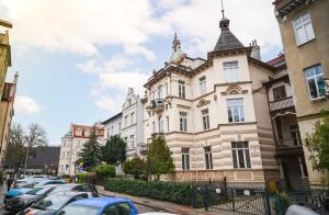 een groot gebouw met auto's geparkeerd voor het bij Caramel by OneApartments in Sopot