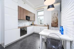 a kitchen with white cabinets and a table and chairs at Caramel by OneApartments in Sopot