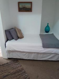 a white bed with pillows and a vase on the wall at UNDERBERG INN in Underberg