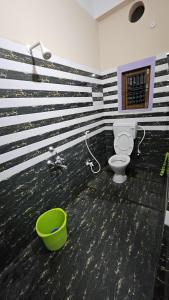 a bathroom with a toilet and a green bucket at Balaji Homestay in Guwahati