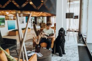 a man sitting in a chair with a dog in a living room at Gabija Hotel SPA & Conferences in Palanga