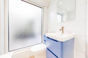 a bathroom with a sink and a toilet and a mirror at Cosy 2Bed garden flat in Wimbledon near the tube in London