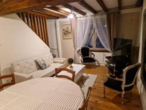 een woonkamer met een bank en stoelen en een televisie bij Charmante petite grange - 5 Couchages in Nalzen