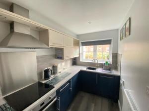 a kitchen with white and blue cabinets and a sink at Arthur's Retreat in Filey