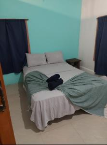Una cama con una manta verde encima. en Casa Anez, en Cabuya