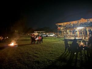un grupo de personas sentadas alrededor de un fuego por la noche en Hill Stone View Hampi en Hampi