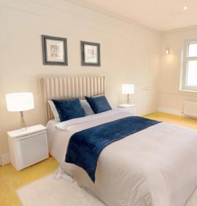a bedroom with a large white bed with blue pillows at Stylish 3 Bedrooms in London