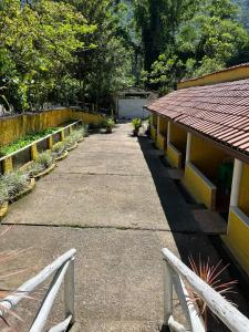 einen Gehweg neben einem Gebäude mit einem Zaun in der Unterkunft Suíte serra dos órgãos guapimirim in Guapimirim