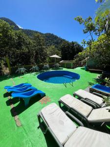 uma piscina com espreguiçadeiras e um relvado verde em Suíte serra dos órgãos guapimirim em Guapimirim
