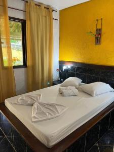 uma grande cama branca num quarto com uma parede amarela em Suíte serra dos órgãos guapimirim em Guapimirim