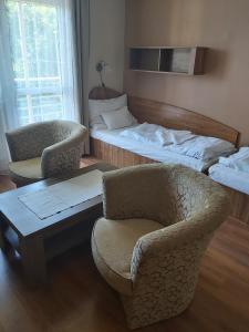 Habitación con 2 camas, silla y mesa. en Solar Club Hotel en Sopron