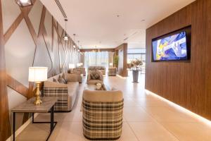 Enala Hotel - Tabuk في تبوك: غرفة معيشة مع أرائك وتلفزيون على الحائط