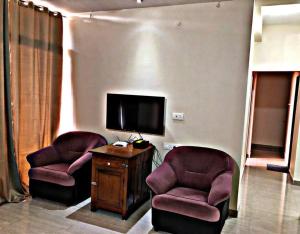 a living room with two chairs and a flat screen tv at EMBASSY G-03 in Belgaum