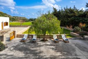 a group of lounge chairs sitting under a tree at Hermes' Getaway Plimmiri in Plimmiri