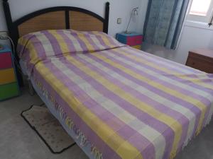 プエルト・デ・マサロンにあるRESIDENCE BAHIA REAL PUERTO de MAZARRONの紫と黄色のチェック毛布付きベッド