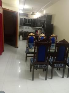 a dining room with blue chairs and a kitchen at Gujrat Guest House in Gujrāt