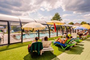 a group of people sitting in lawn chairs by a pool at Budget Glamping Safaritent La Sténiole in Barbey-Séroux