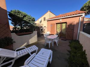 a patio with white chairs and a table and chairs at Villa T3 avec terrasse, 6 couchages, proche plage et commerces, quartier calme, parking privé - FR-1-81-365 in Port Leucate