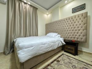 um quarto com uma cama grande e uma grande cabeceira. em Pyramids Gardens Hotel - فندق حدائق الاهرام no Cairo