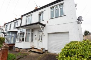 a white house with a garage at Apartment with Free parking - 6 min drive to beach! in Southend-on-Sea