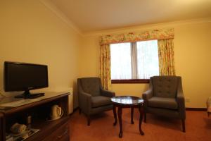 a living room with two chairs and a television at Strathburn Hotel Inverurie by Compass Hospitality in Inverurie