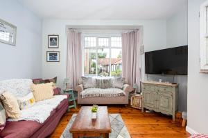 a living room with a couch and a tv at Apartment with Free parking - 6 min drive to beach! in Southend-on-Sea
